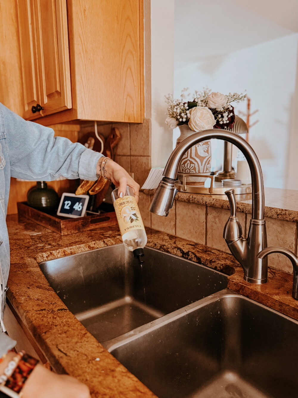 woman squirting dish soap into a stainless steel sink