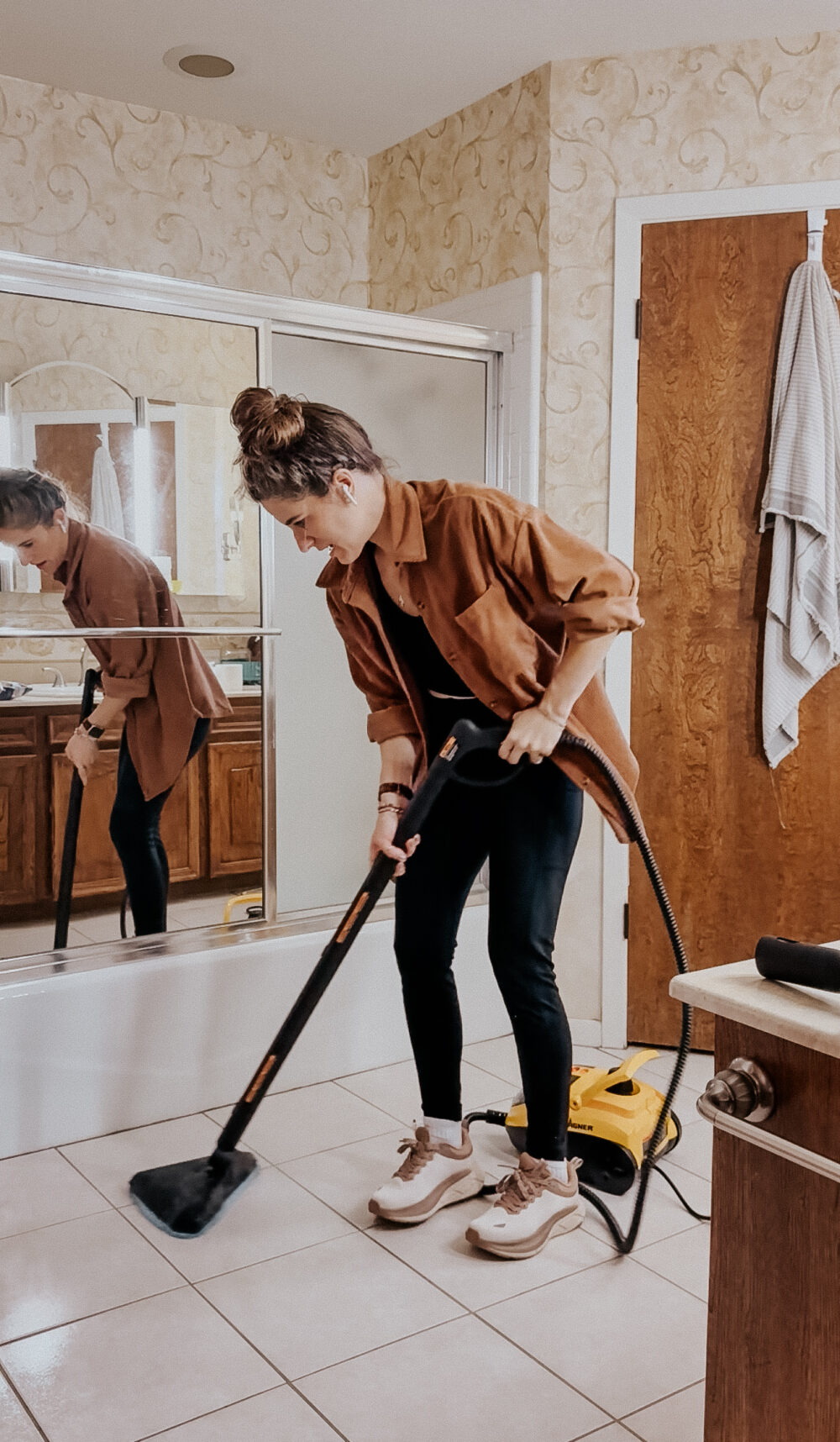 woman steam cleaning a bathroom floor using a Wagner steam cleaner
