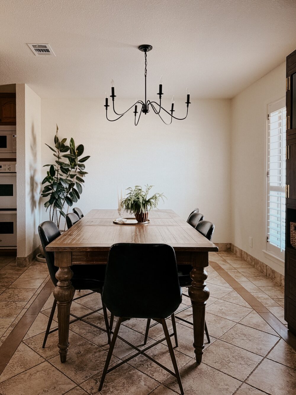 dining room with white walls, a awood table and a black chandelier