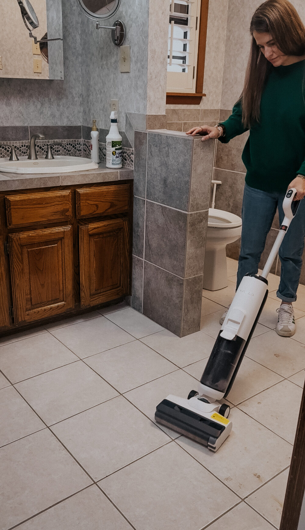woman cleaning a dirty bathroom floor with a tineco ifloor breeze