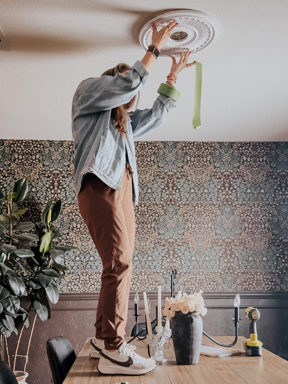 woman attaching a ceiling medallion to the ceiling in a 1970's home
