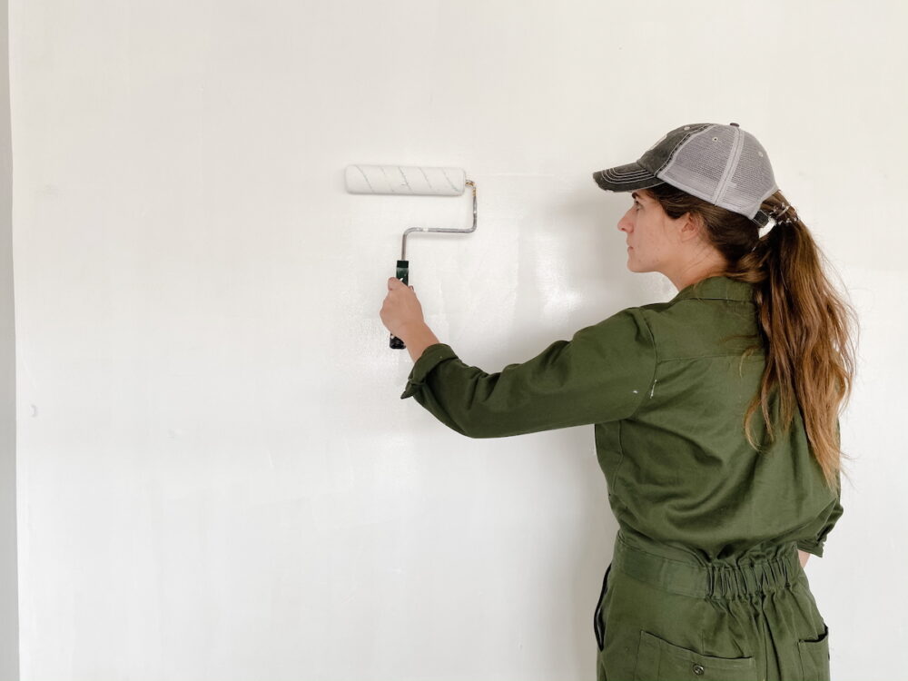 Woman using a paint roller to touch up paint on a wall