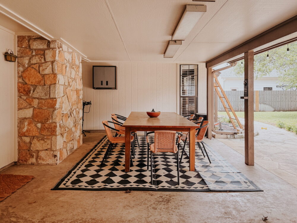 large back patio with a dining table, chairs, and a checkered rug