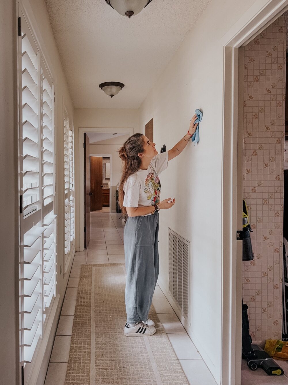 woman in a hallway using a cloth to clean the walls