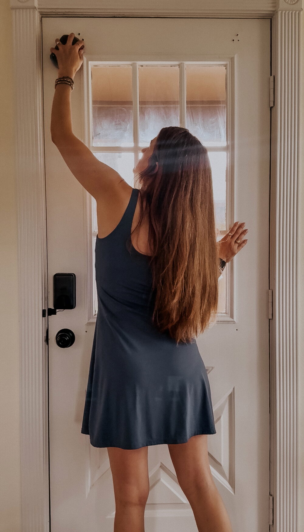 woman using a sanding block to sand holes in a metal door