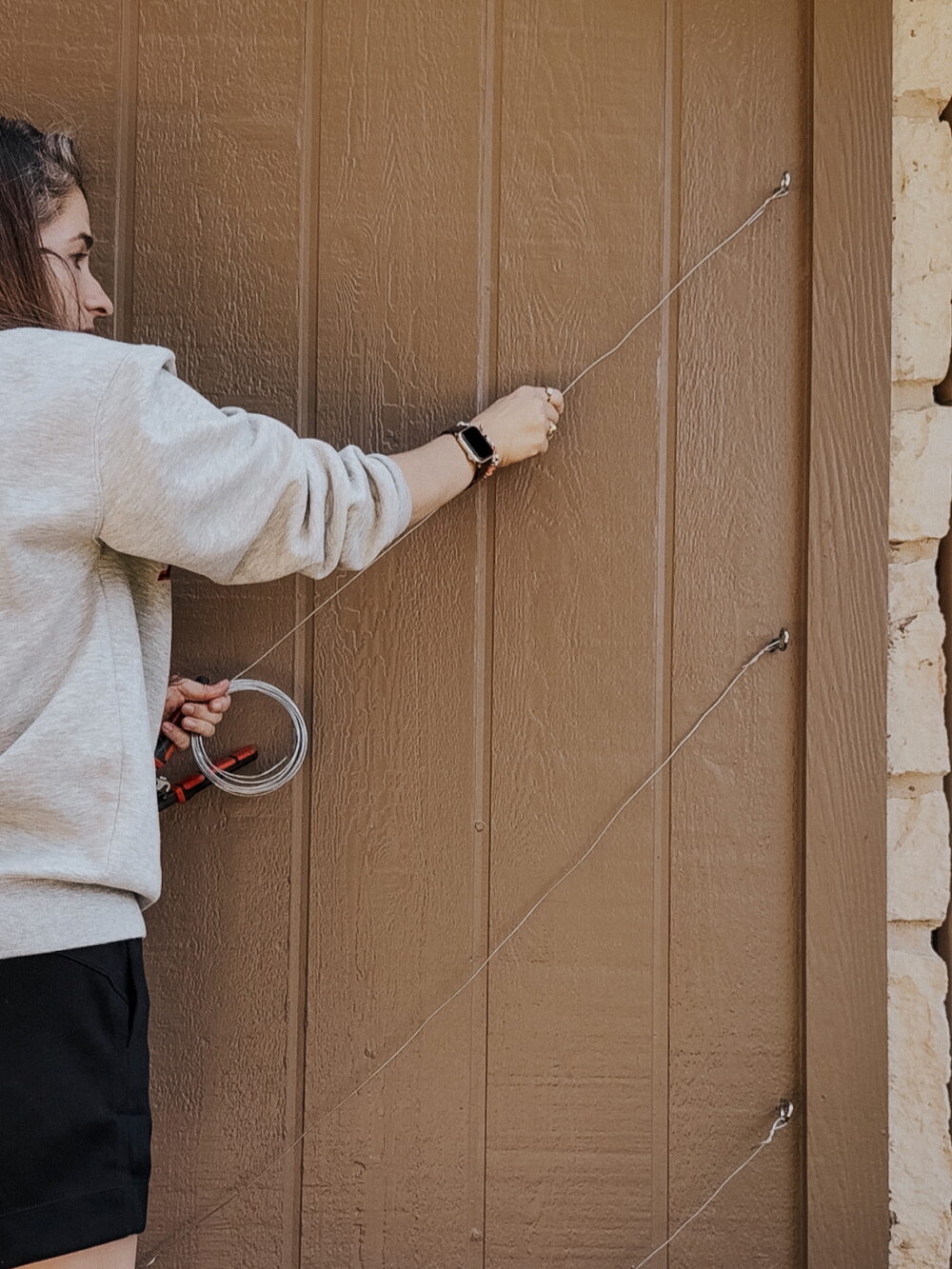 woman installing wire on grid for trellis