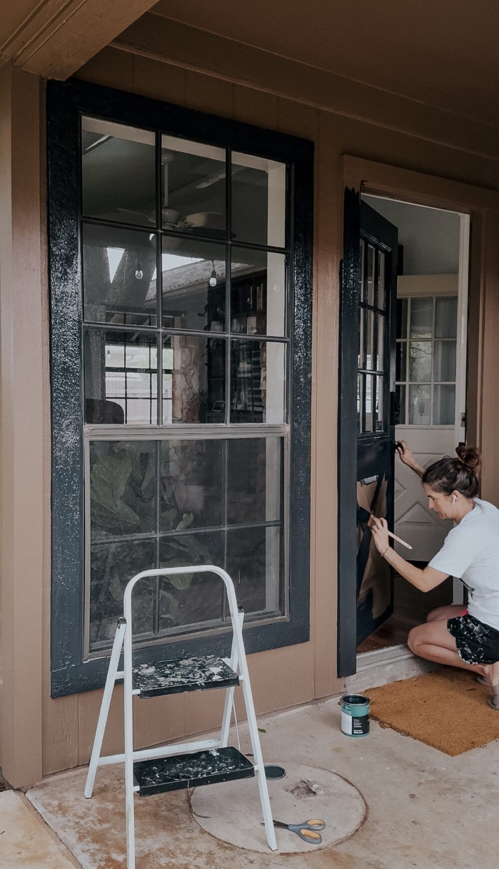 woman painting an exterior door with a paintbrush