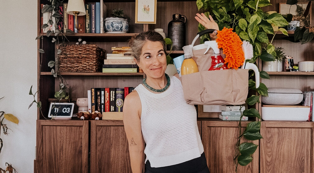 woman smiling and holding a cleaning caddy