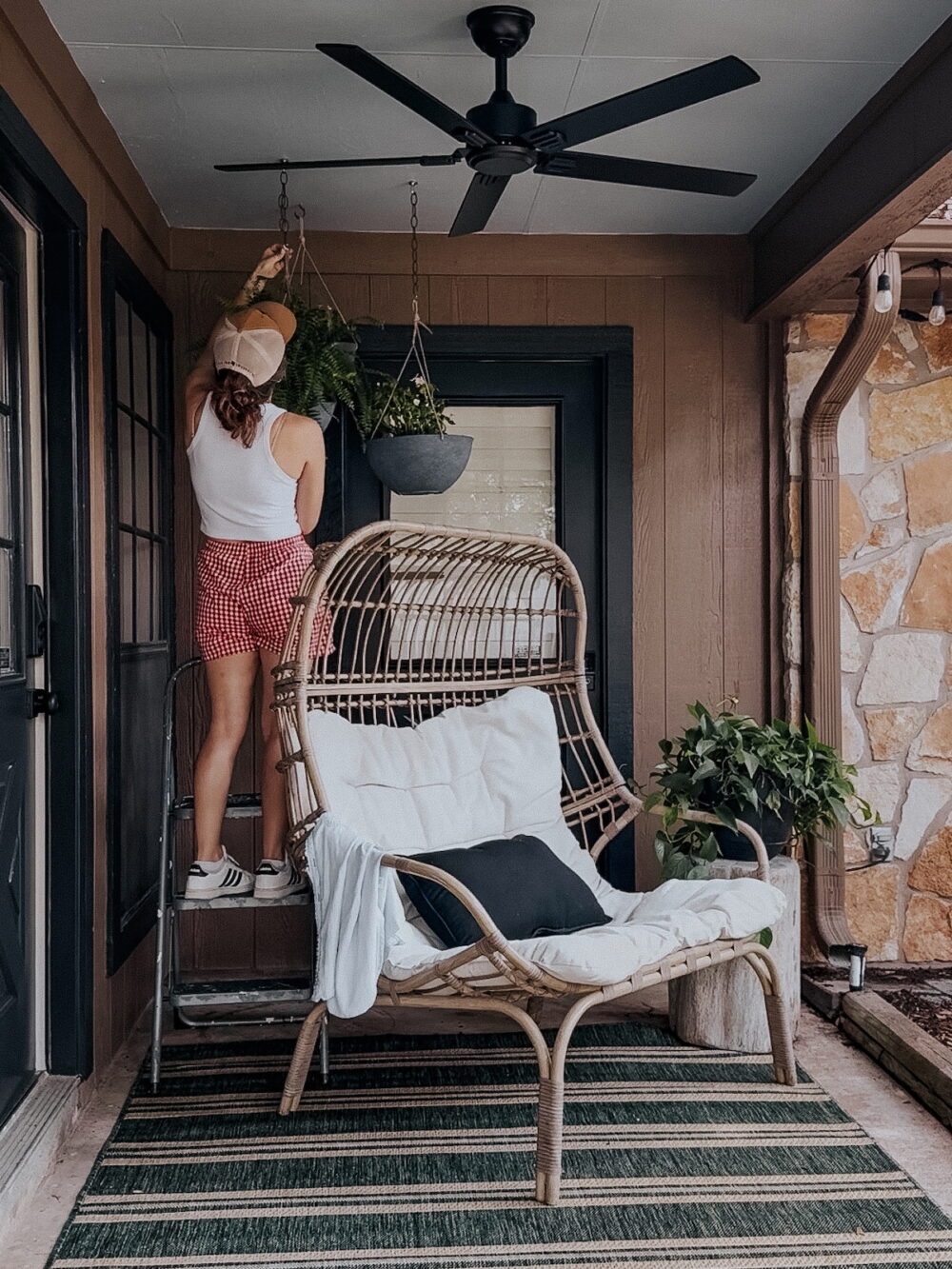 woman hanging an outdoor planter on a small patio