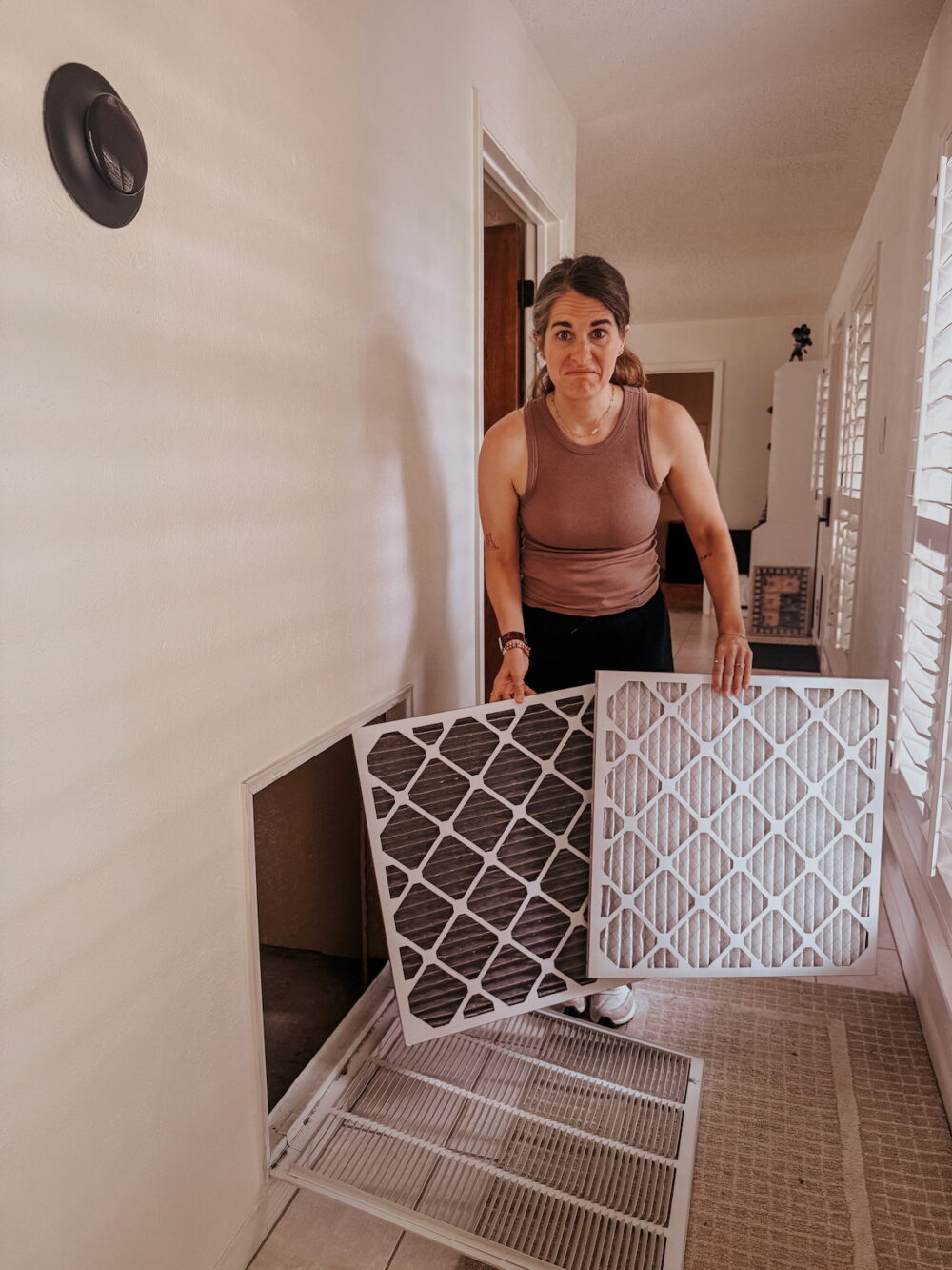 woman holding up a dirty air filter and a clean air. filter