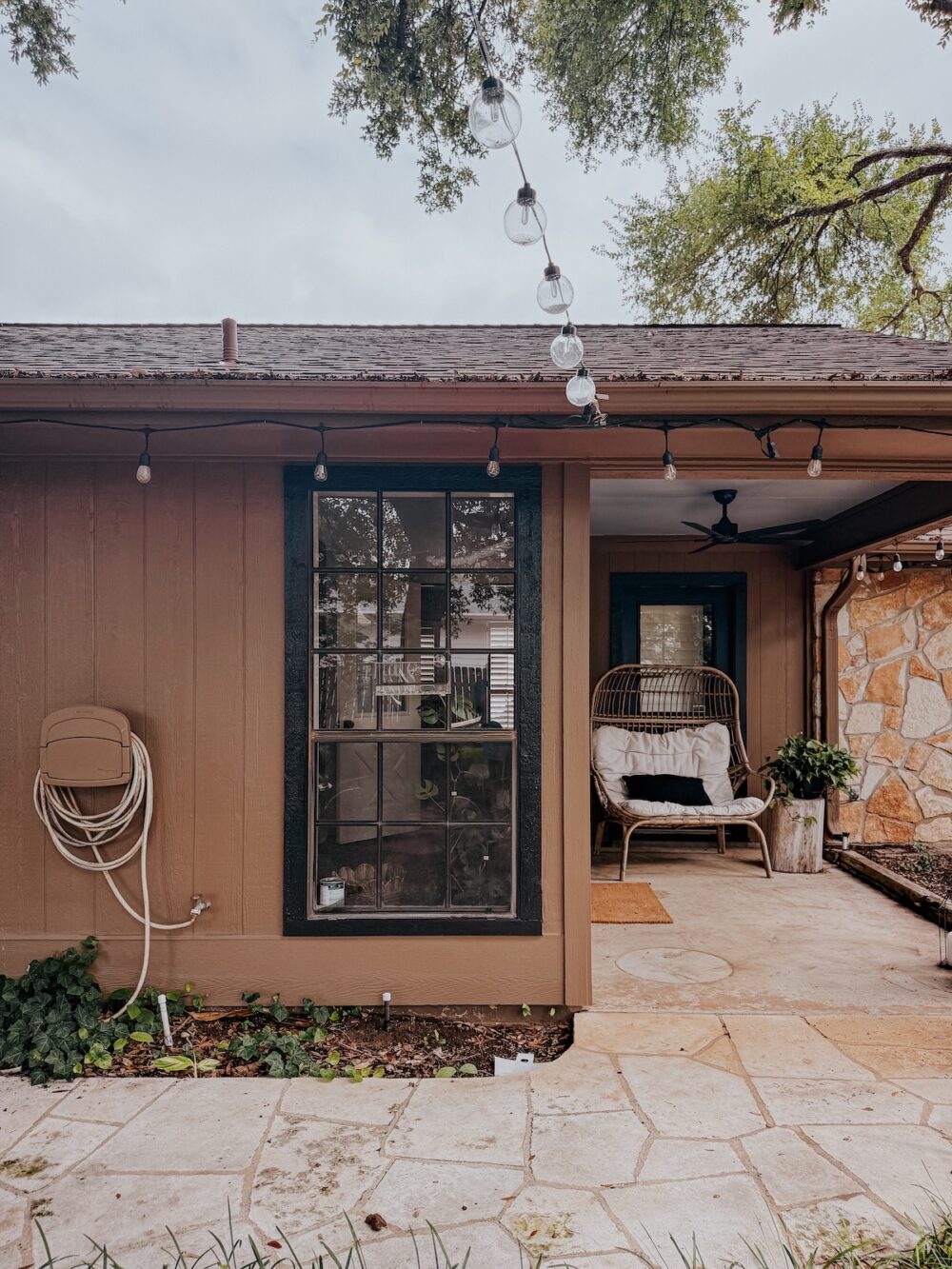 brown house with black trim and a small patio