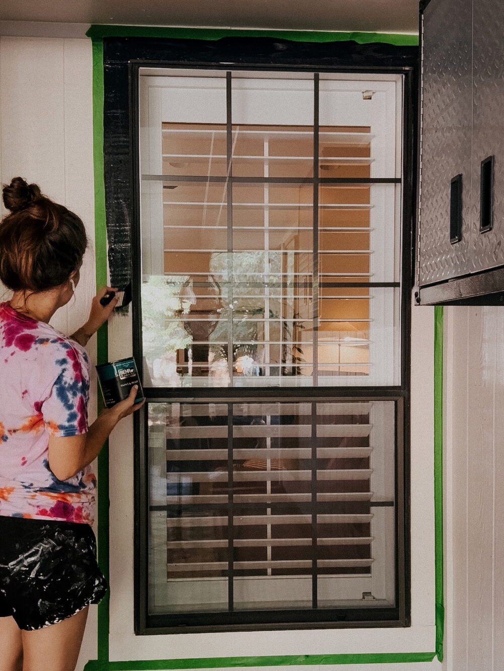woman painting window trim black