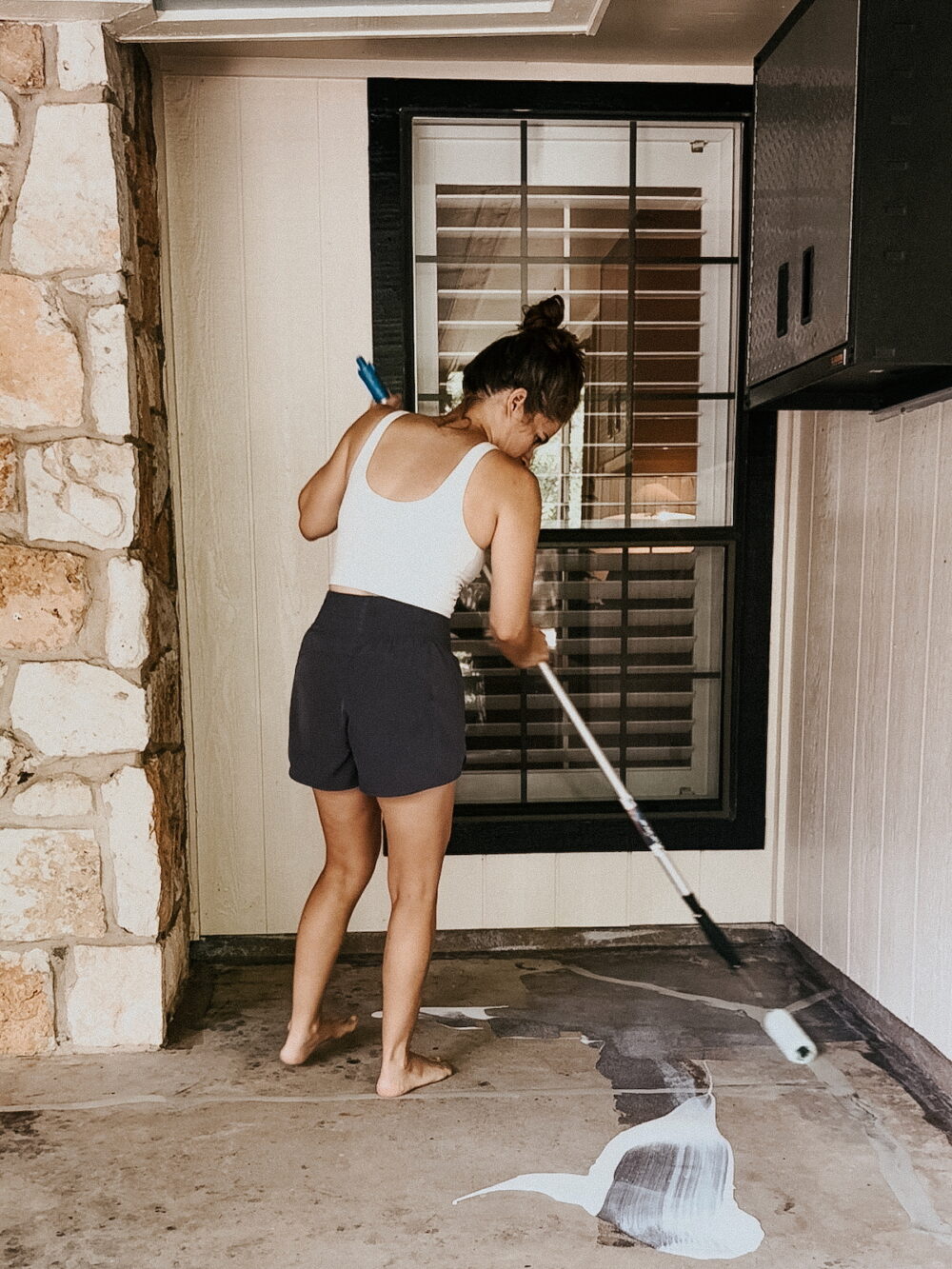 woman priming a concrete patio before painting