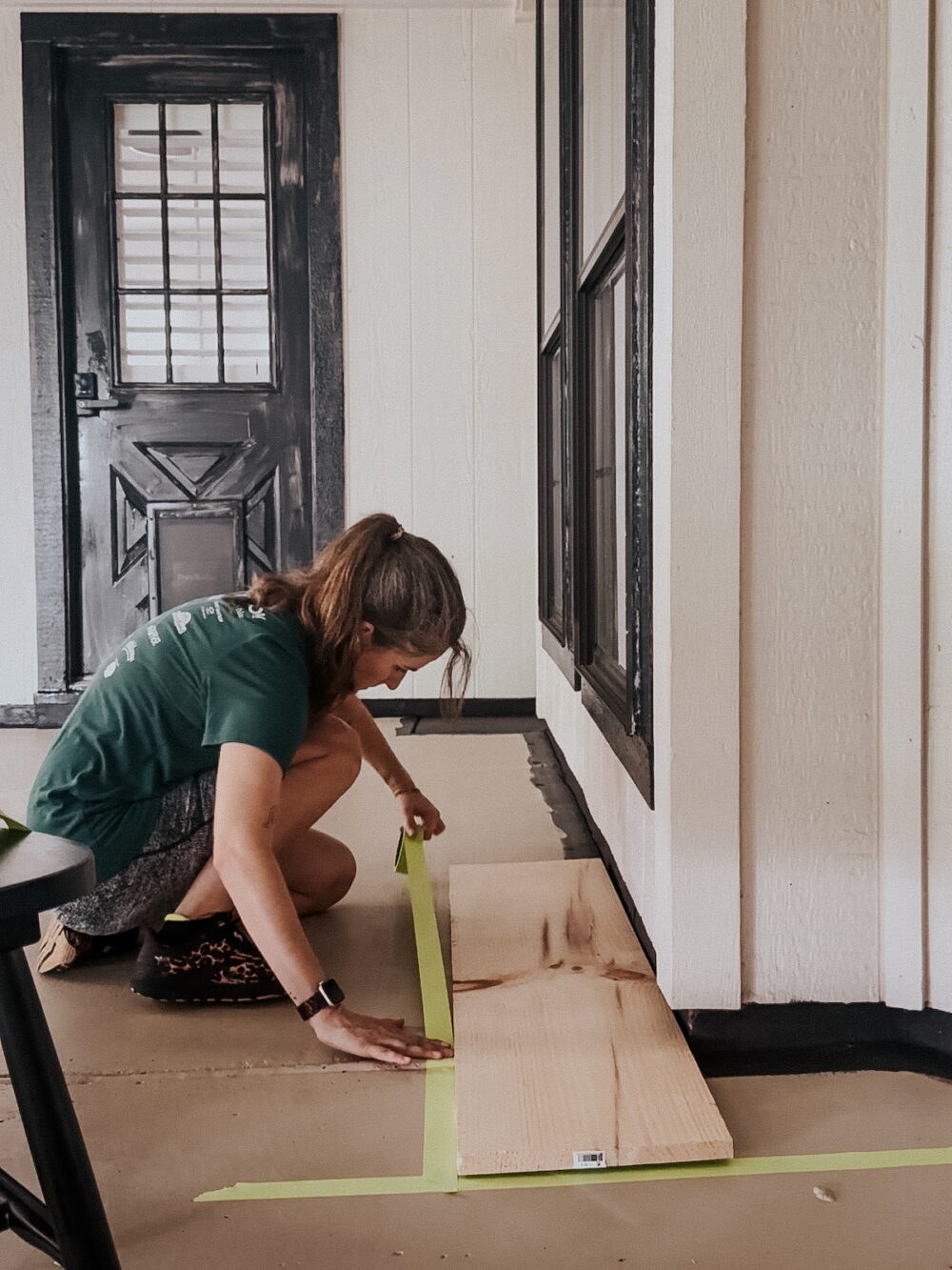 woman taping off a border on a painted concrete patio