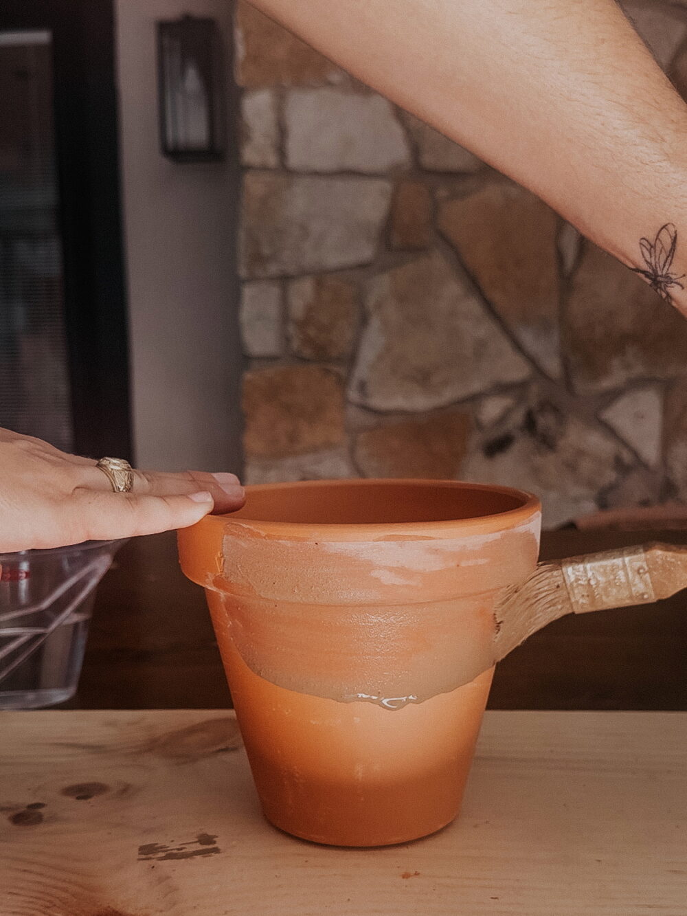 woman applying garden lime to a terra cotta pot to age it