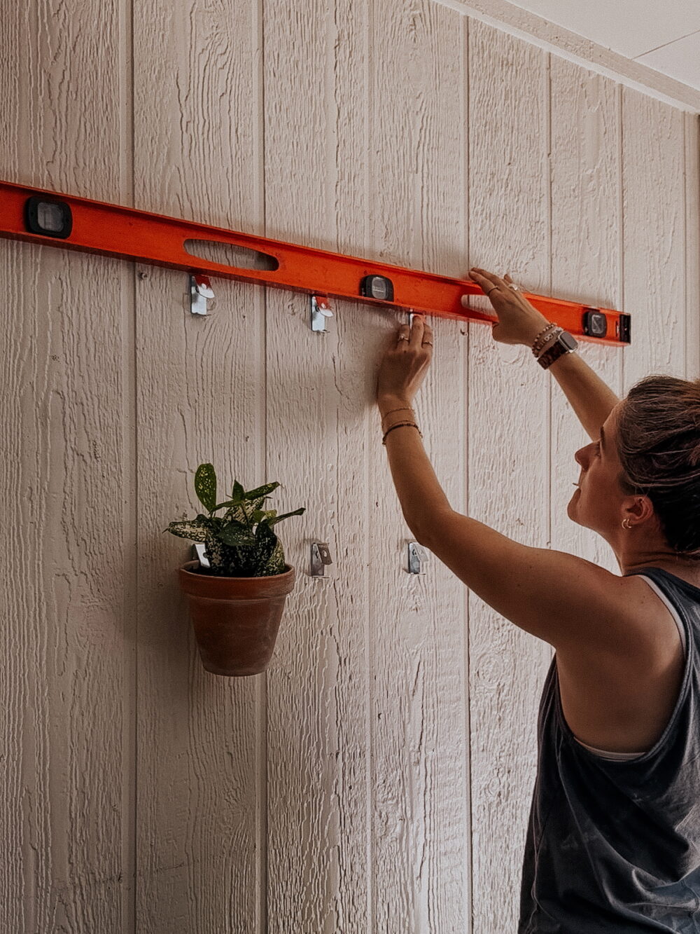 woman hanging a pot clip on a patio wall