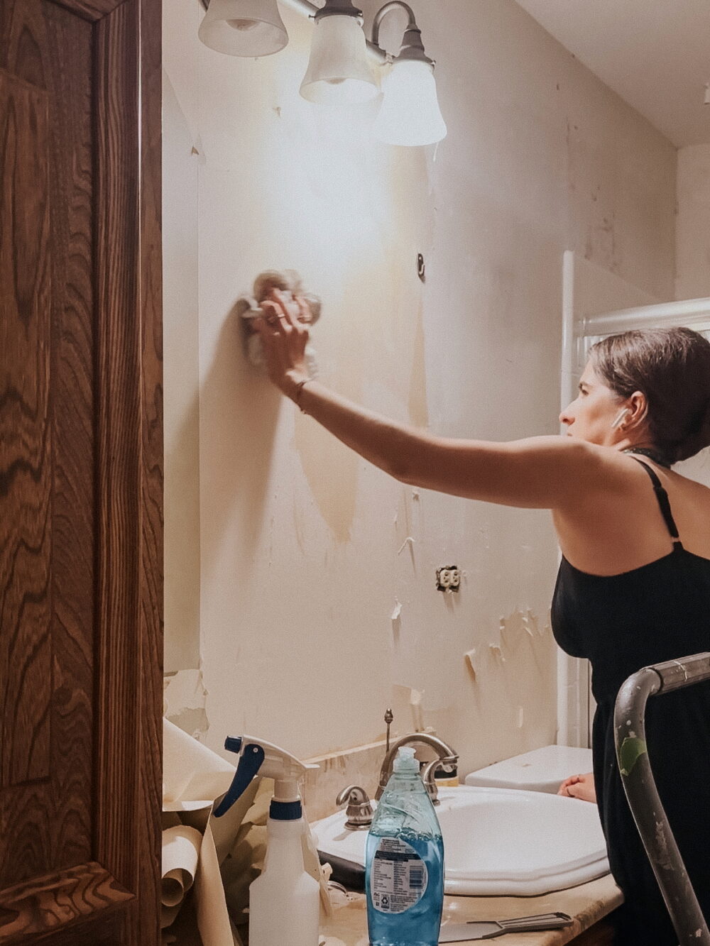 woman cleaning a wall after wallpaper removal