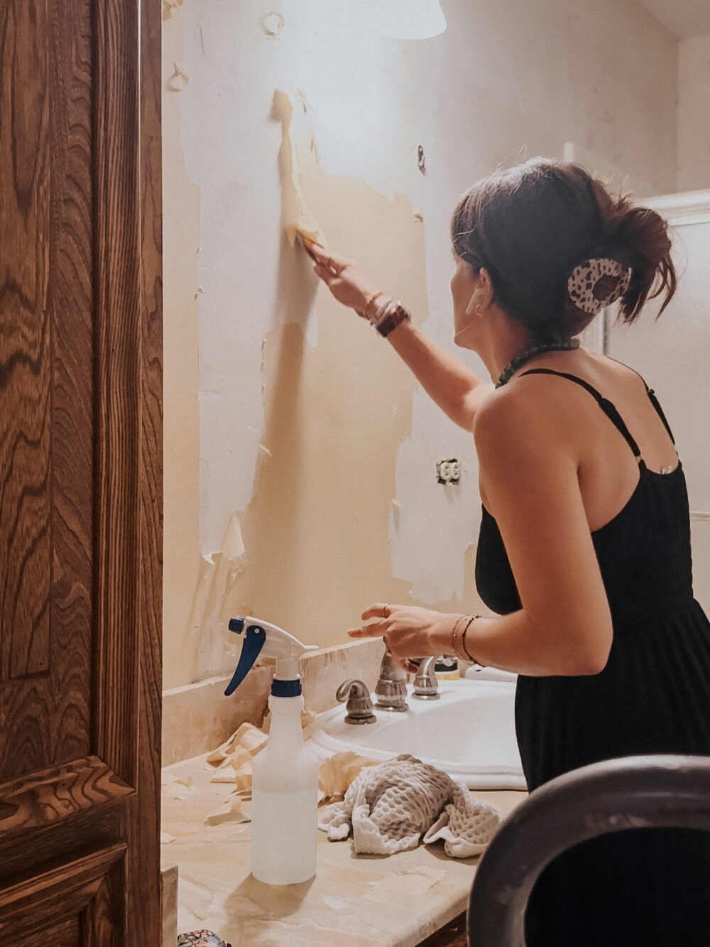 woman using a plastic scraper to remove wallpaper from the wall