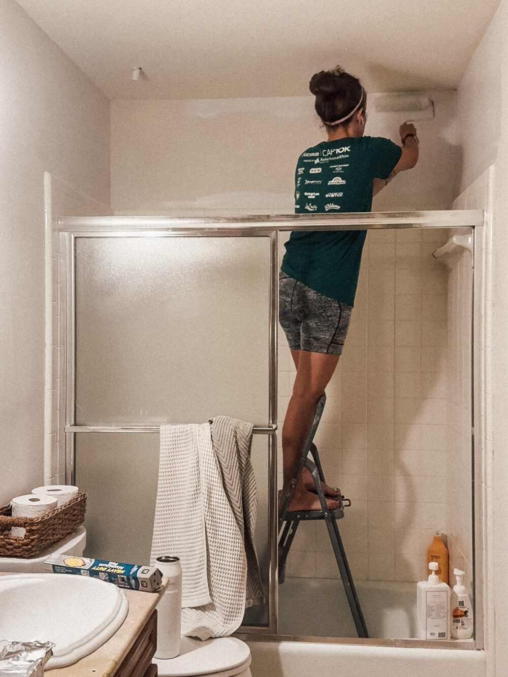woman priming a bathroom wall
