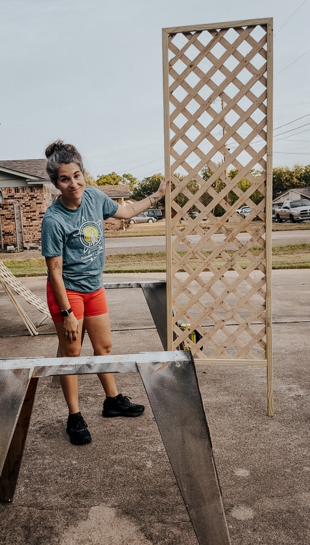 Woman holding a tall trellis for the side of a house