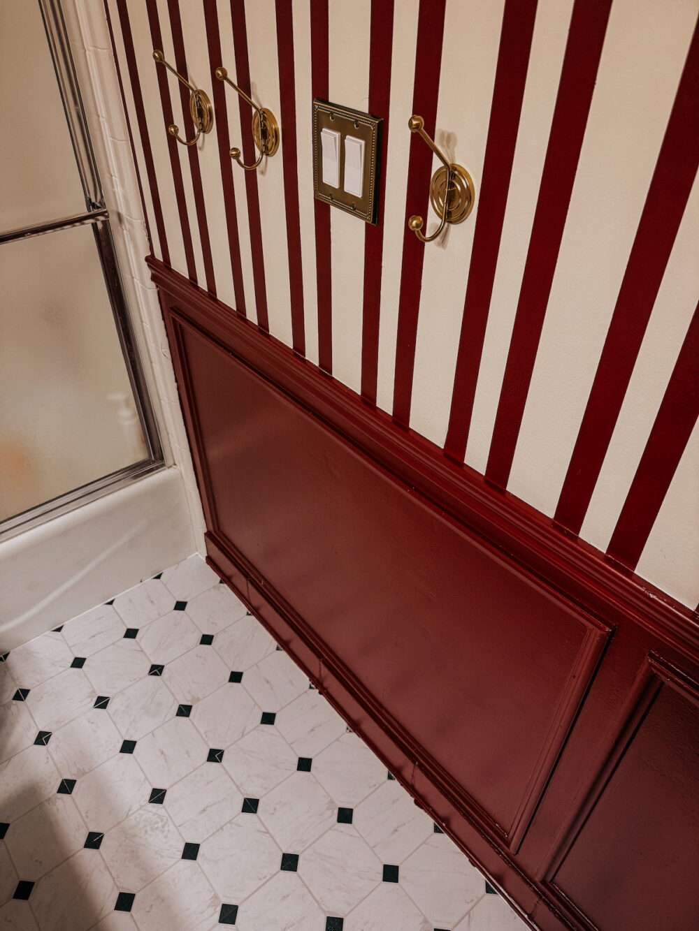 small bathroom with red and white striped walls and floor pop Chris Loves Julia x FloorPops Cricket peel and s tick tiles