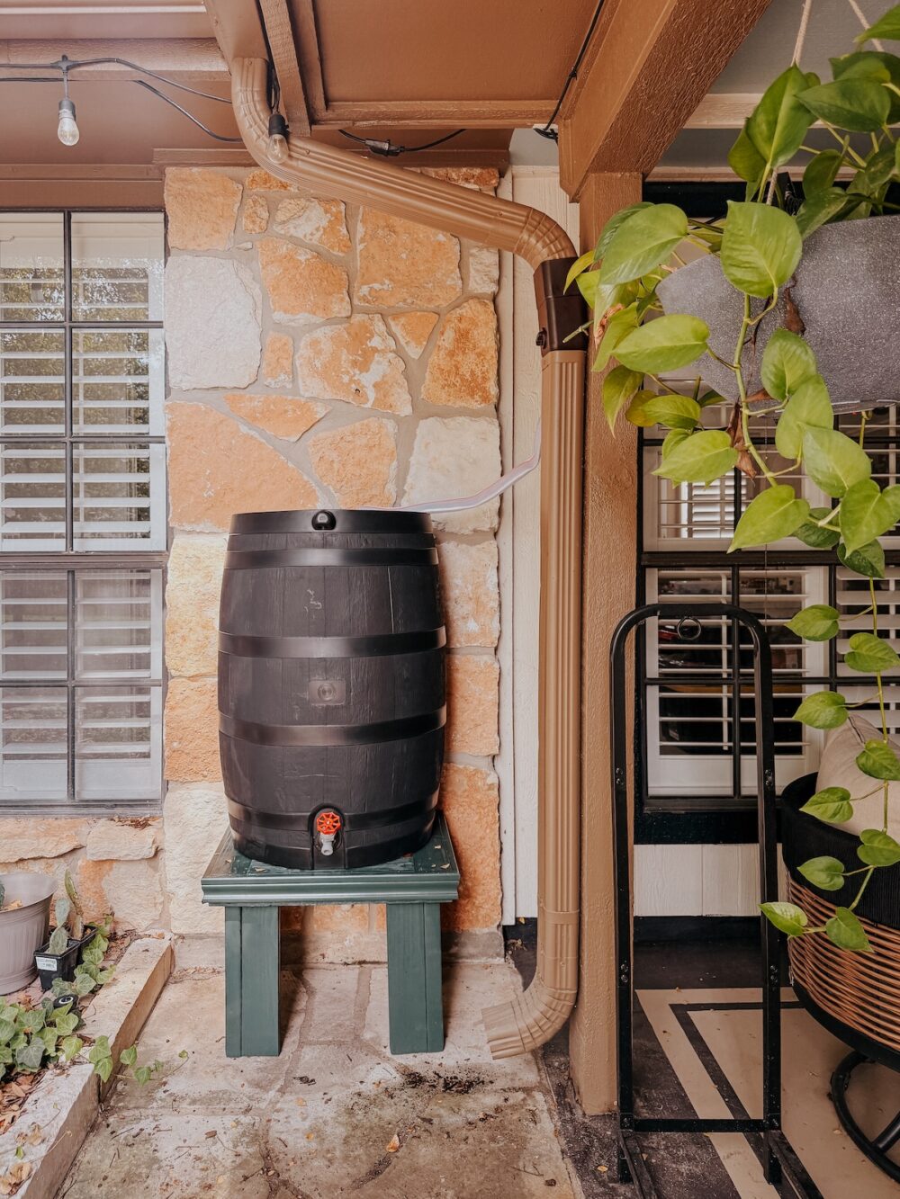 plastic rain barrel sitting on a wooden stand