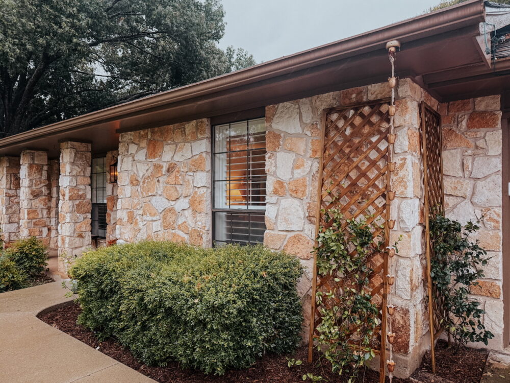 front of a stone house with a rain chain on the corner