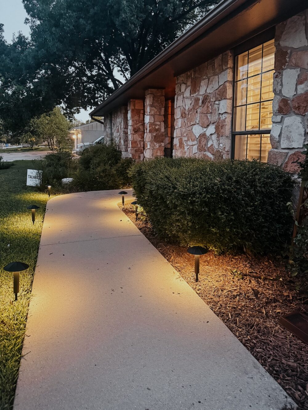 home with pathway lights next to the sidewalk leading up to the house
